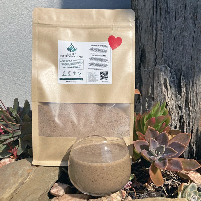 Eco-friendly kraft paper pouches of Organic Vegan Superfood Blend, 500g, with a red heart label, photographed outdoors in natural light.